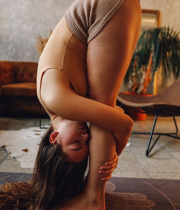 Person stretching gently on a yoga mat in a cozy setting.