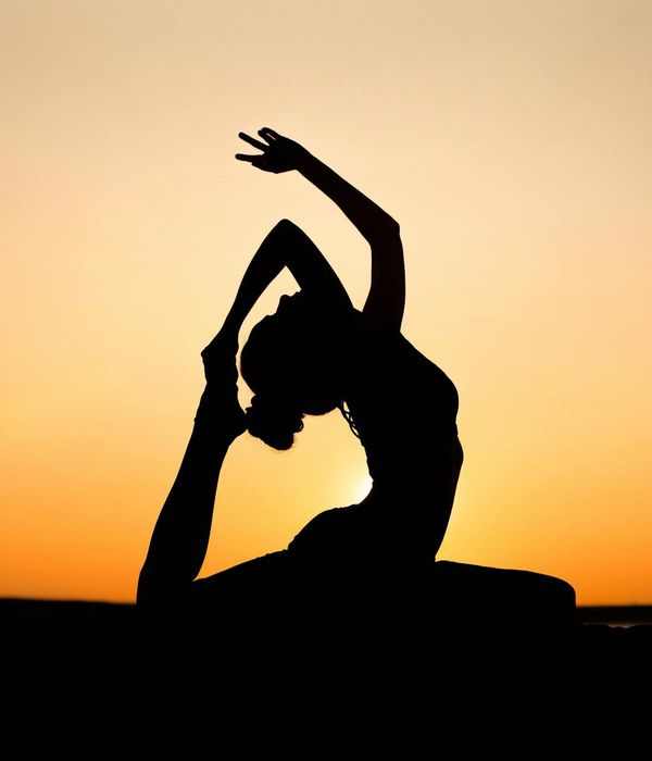 Silhouette of a person in a yoga warrior pose at sunset.