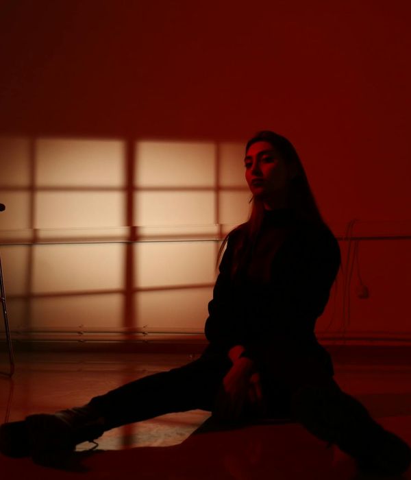 Woman in a calm, seated yoga pose in a dark room.